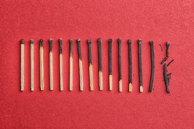 Photo of Row of burnt matches and whole one on color background, flat lay. Human life phases concept