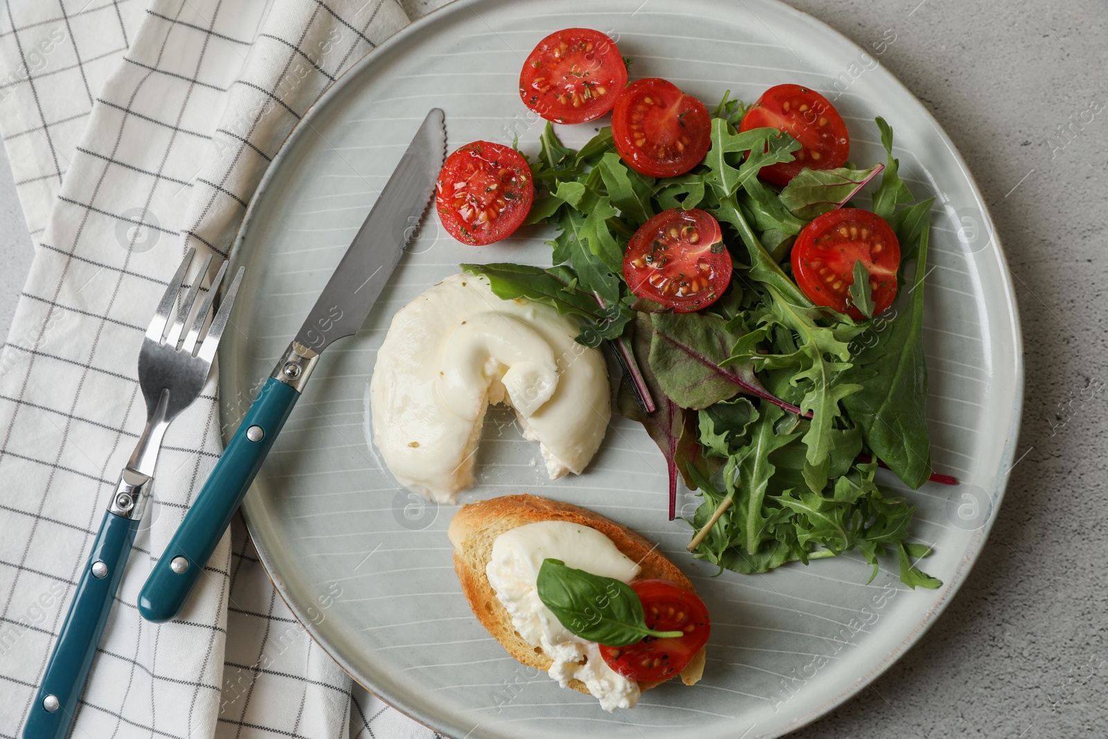 Photo of Delicious burrata cheese with tomatoes, arugula and toast served on grey table, top view