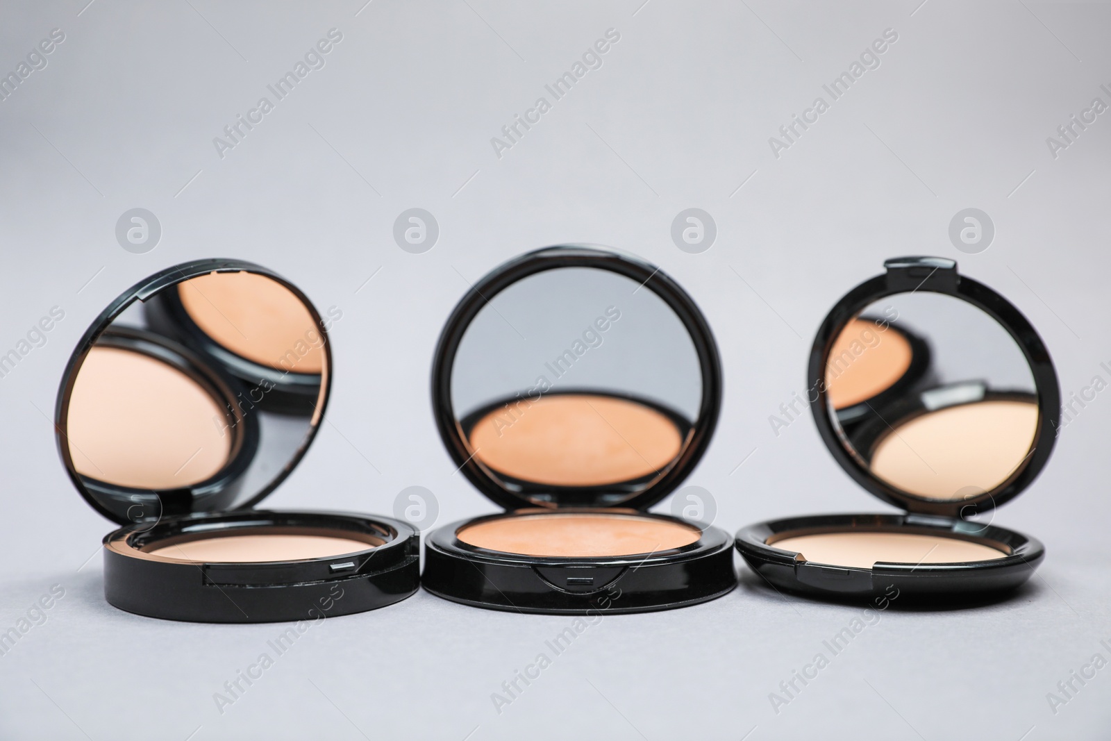 Photo of Open face powders with mirrors on light grey background