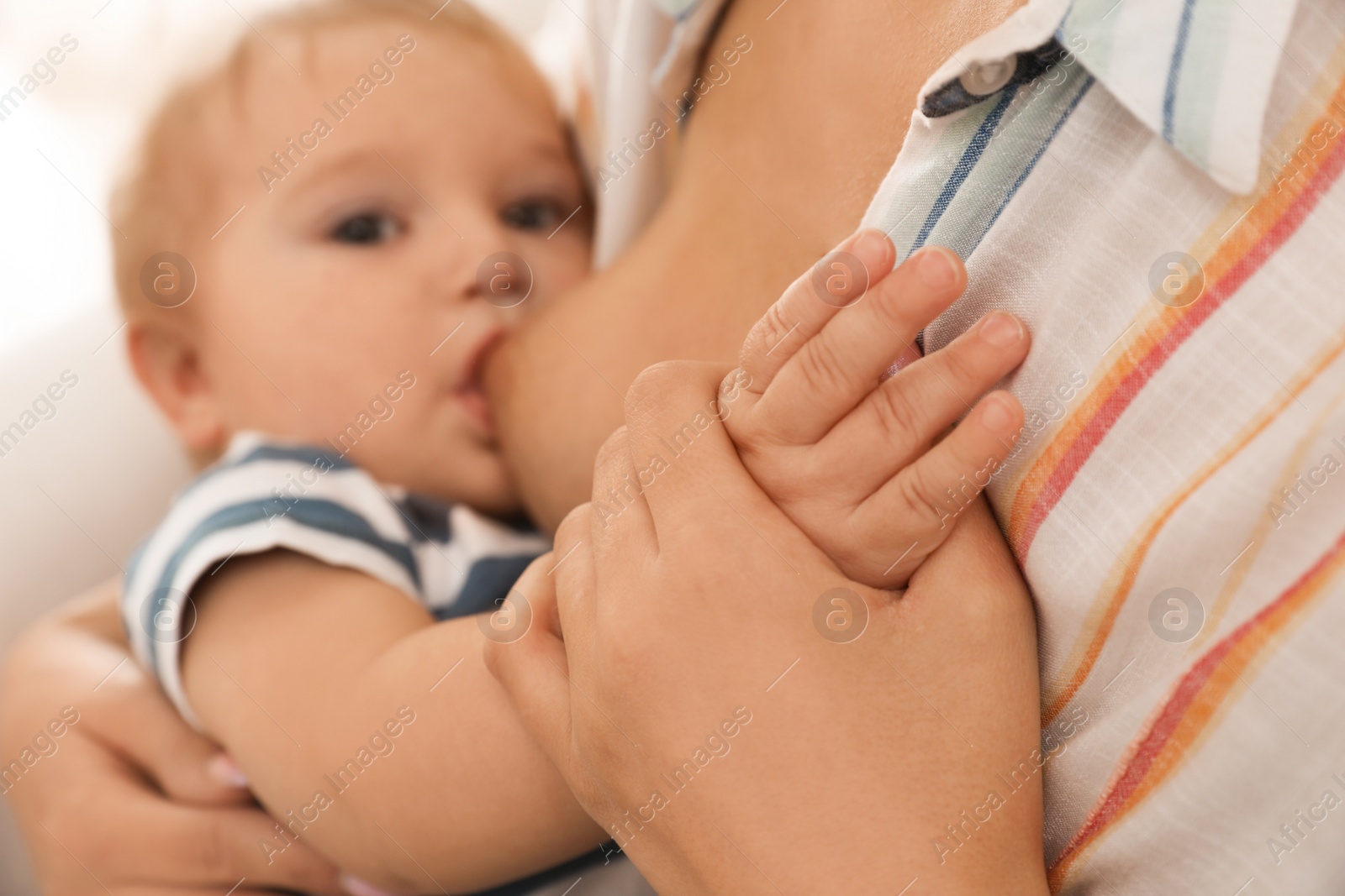 Photo of Woman breastfeeding her little baby, focus on hands