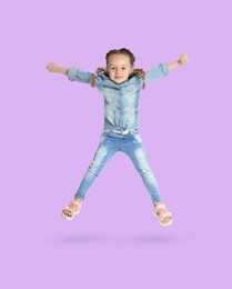 Happy cute girl jumping on light violet background