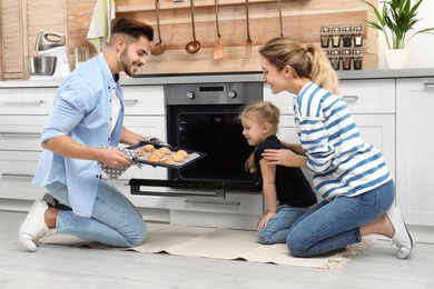 Photo of Happy family baking cookies in oven at home