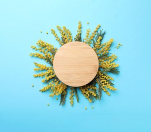 Photo of Beautiful floral composition with mimosa flowers and wooden board on light blue background, flat lay. Space for text