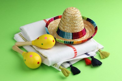 Mexican sombrero hat, maracas and poncho on green background