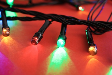 Photo of Glowing Christmas lights on color background, closeup