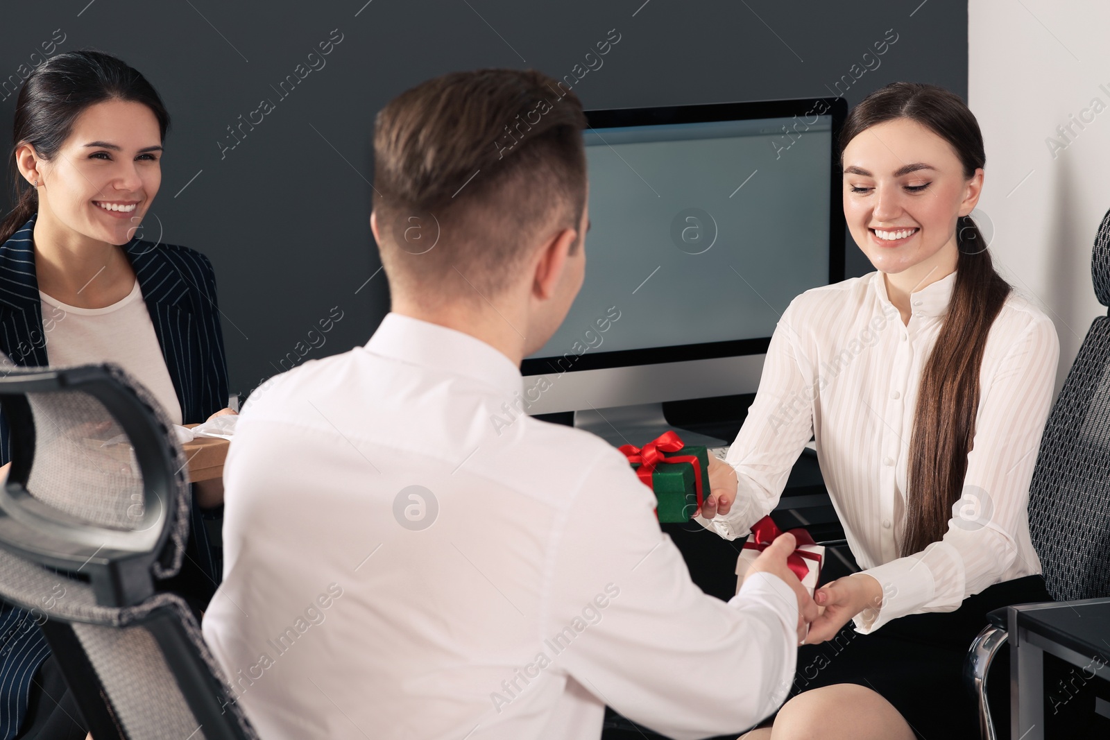 Photo of Colleagues presenting gifts each other in office