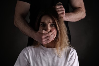 Man abusing scared woman on black background. Domestic violence