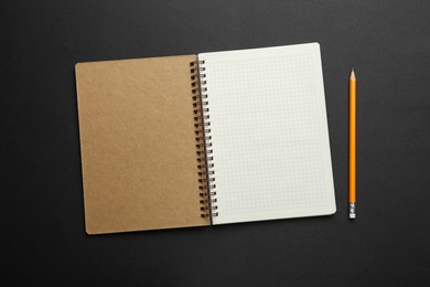 Notebook and pencil on black background, top view