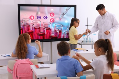 Photo of Teacher and pupils in classroom with interactive board during practical lesson