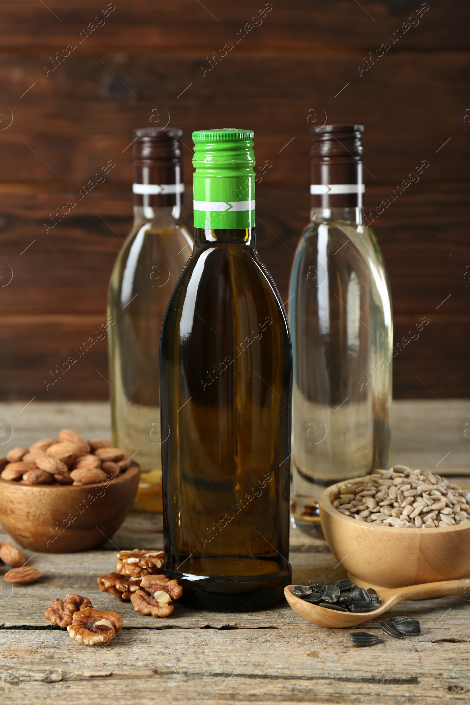 Photo of Vegetable fats. Different cooking oils in glass bottles and ingredients on wooden table