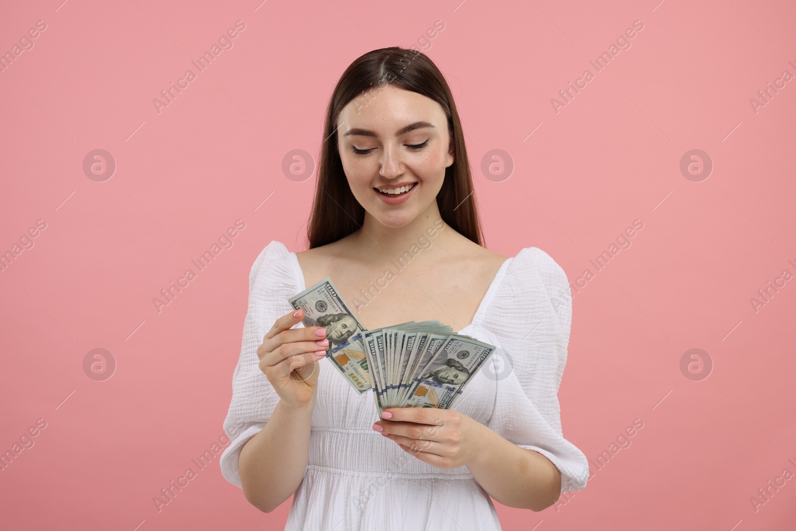 Photo of Happy woman with dollar banknotes on pink background