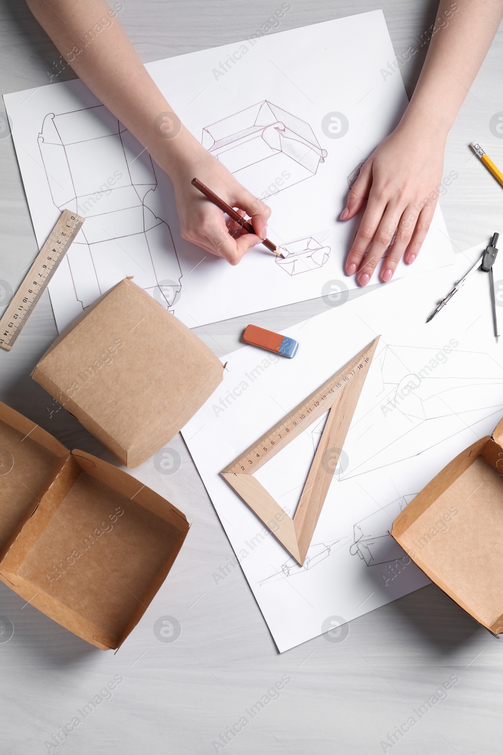 Photo of Woman creating packaging design at light wooden table, top view