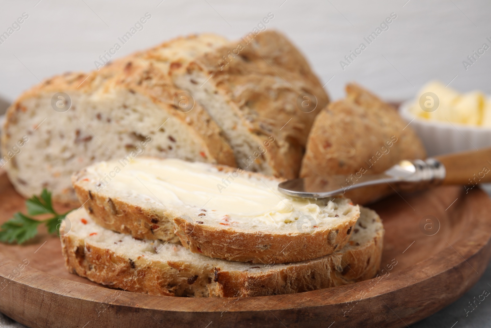 Photo of Tasty bread with butter and knife on table, closeup