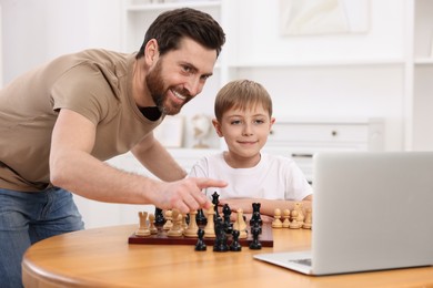 Photo of Father teaching his son to play chess following online lesson at home