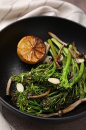 Photo of Tasty cooked broccolini with lemon and mushrooms on table, closeup
