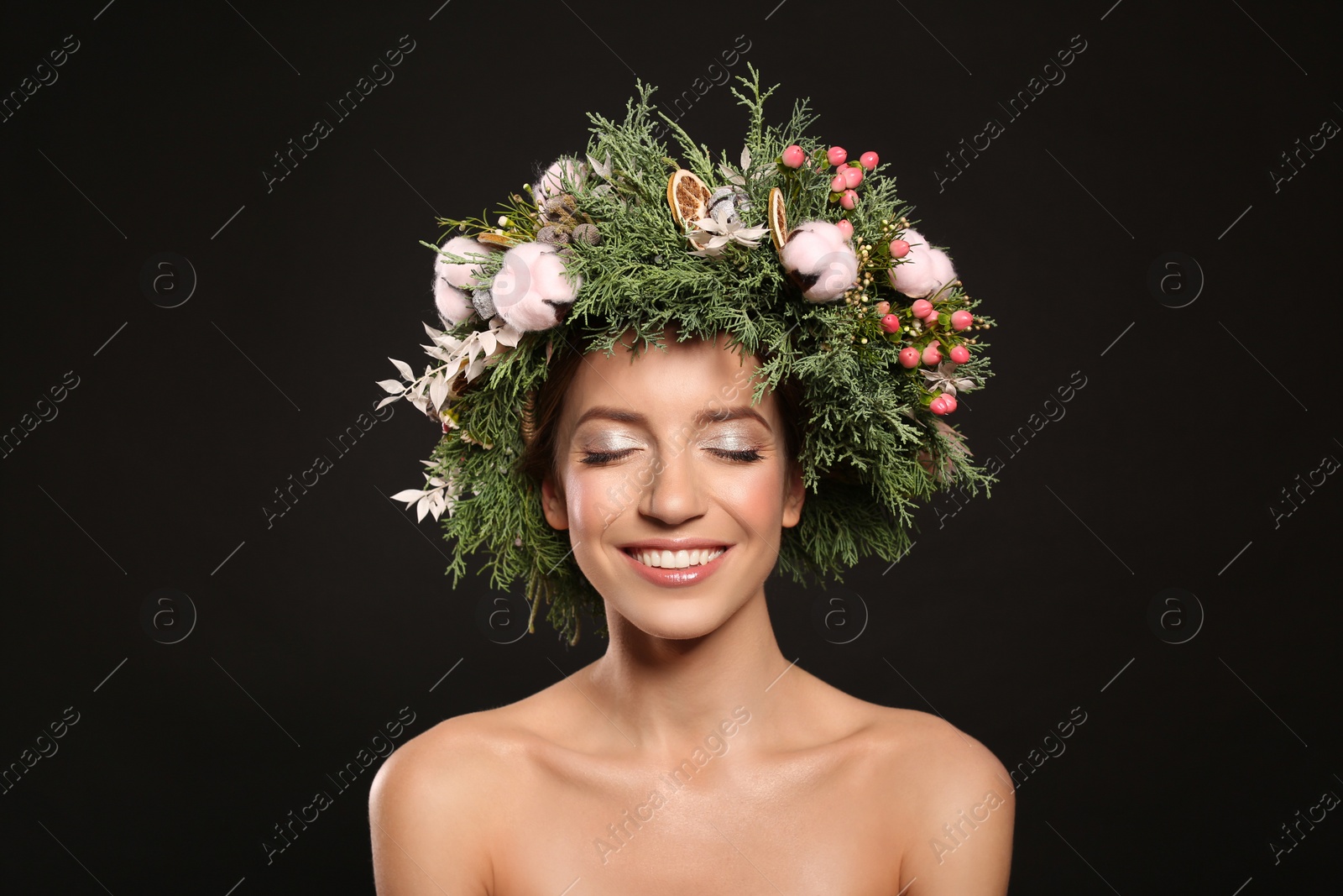 Photo of Happy young woman wearing wreath on black background