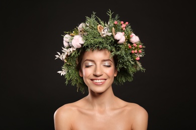 Photo of Happy young woman wearing wreath on black background