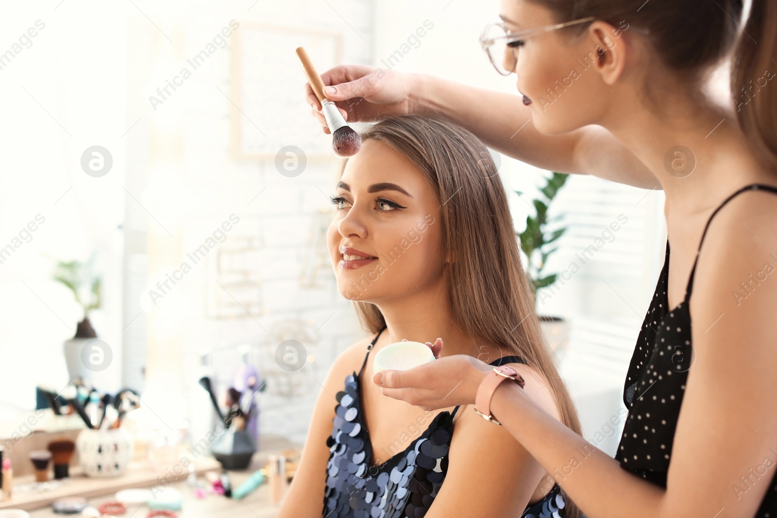 Photo of Professional makeup artist working with beautiful young woman in studio