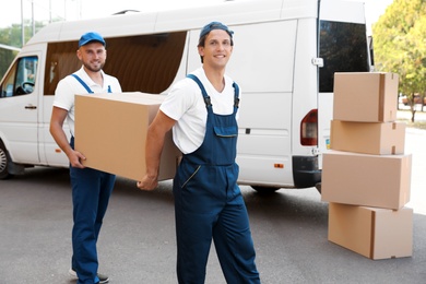 Male movers unloading boxes from van outdoors