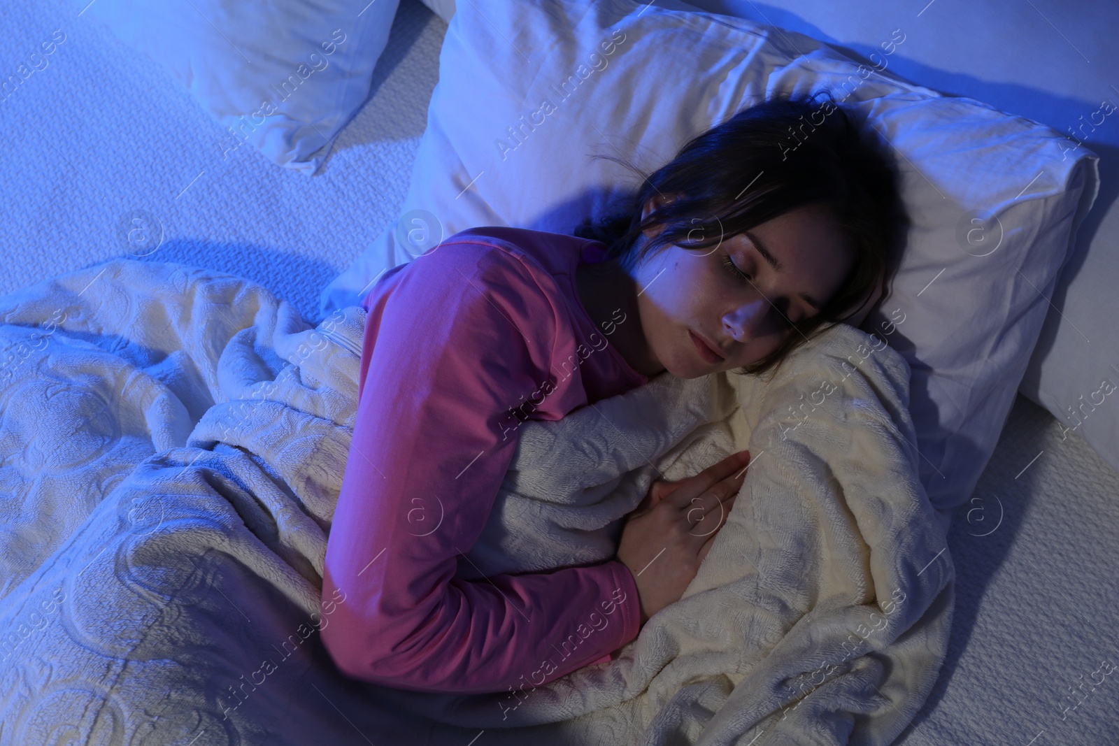 Photo of Young woman sleeping in soft bed at night