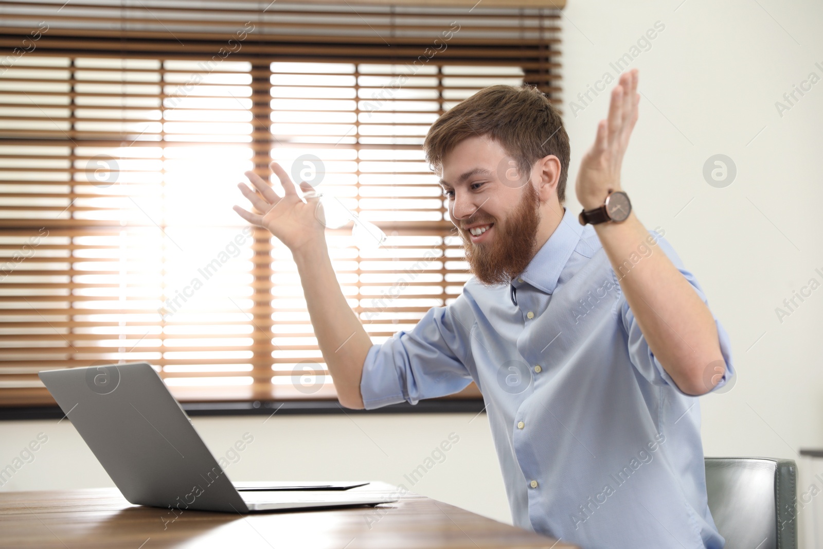 Photo of Man using video chat on laptop in home office