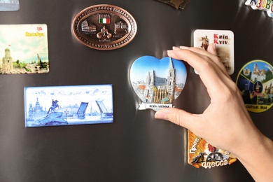 Photo of MYKOLAIV, UKRAINE - DECEMBER 25, 2018: Woman putting magnet on fridge door, closeup