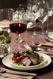 Photo of Delicious grilled meat with vegetables and wine served on table in restaurant