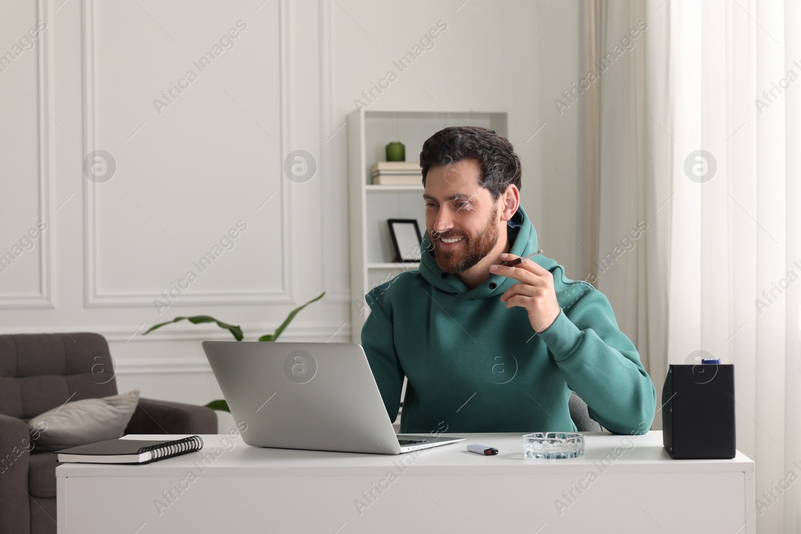 Photo of Man using cigarette holder for smoking at workplace in office