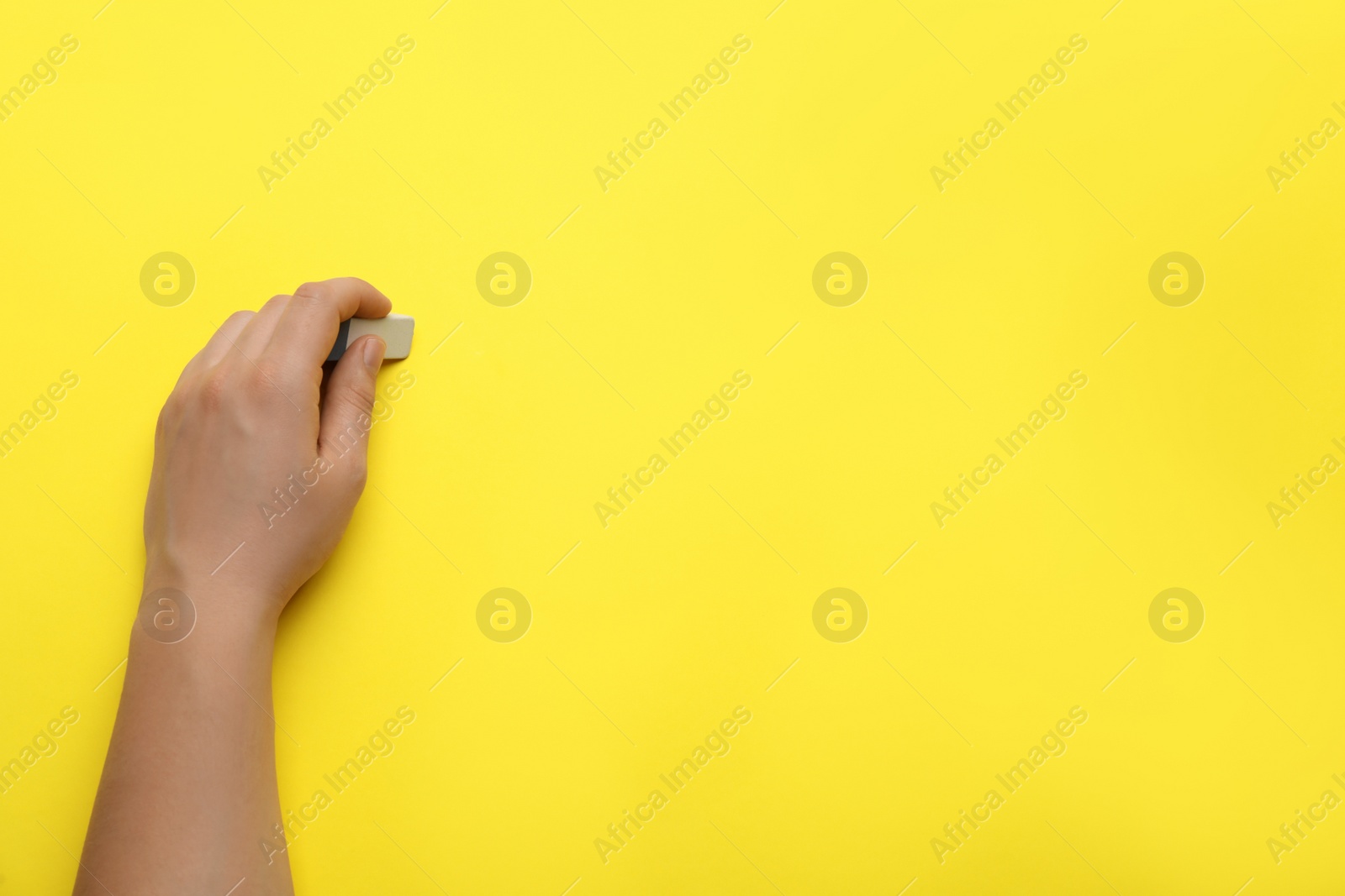 Photo of Man erasing something on yellow background, closeup. Space for text