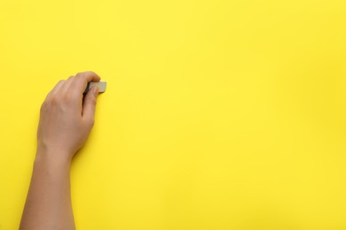 Photo of Man erasing something on yellow background, closeup. Space for text