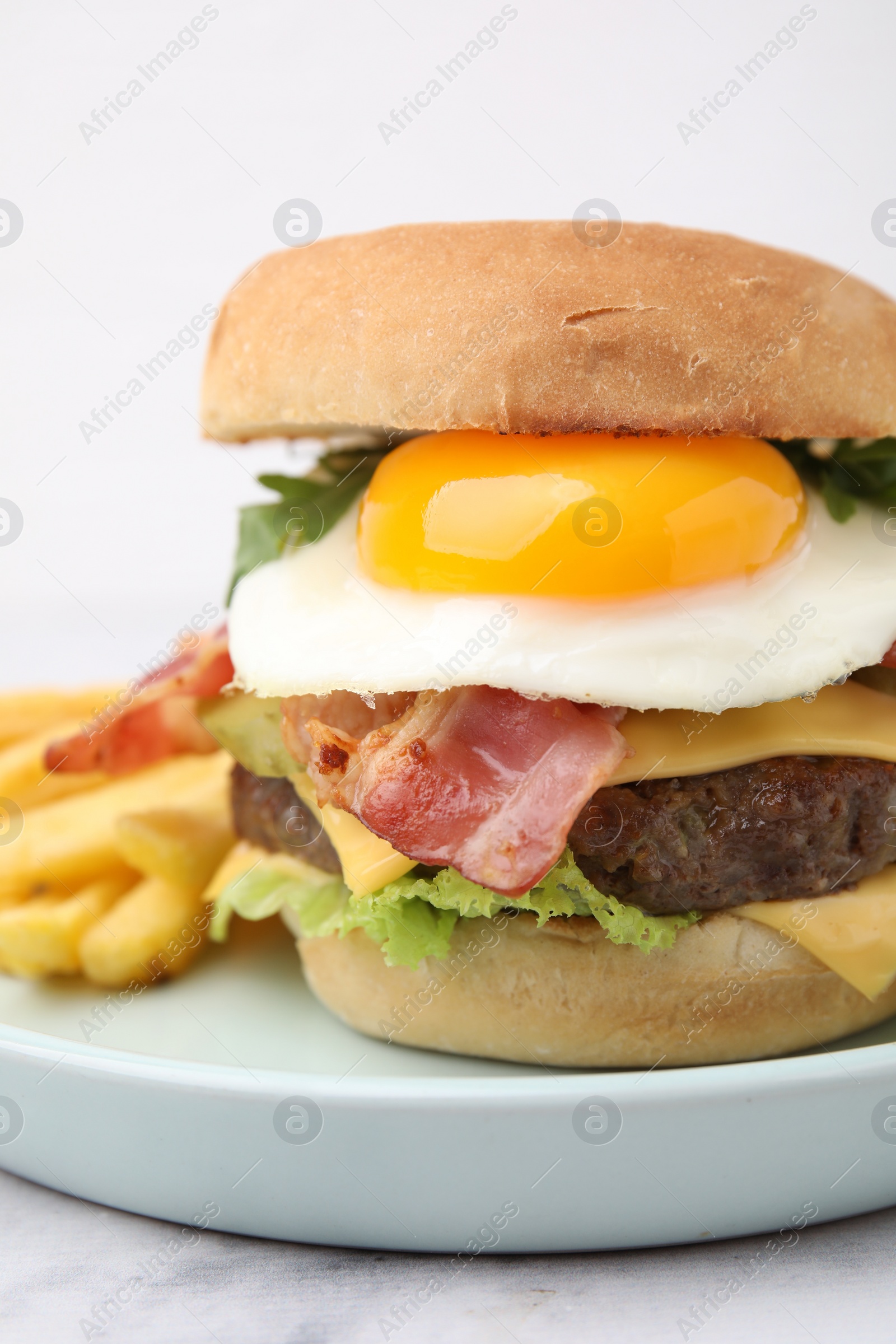 Photo of Delicious burger with fried egg and french fries served on white marble table, closeup