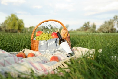 Photo of Picnic blanket with delicious food and wine on green grass