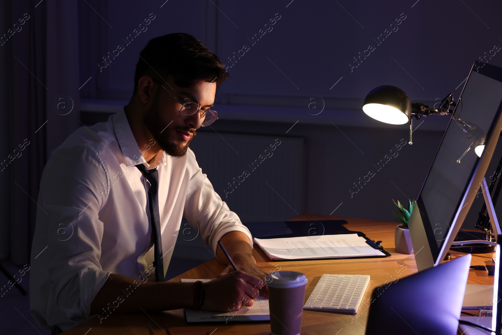 Photo of Tired young man working late in office