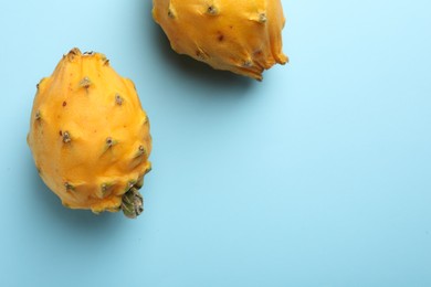 Photo of Delicious yellow pitahaya fruits on light blue background, flat lay. Space for text