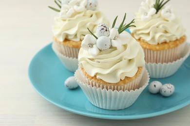 Tasty Easter cupcakes with vanilla cream on light wooden table, closeup