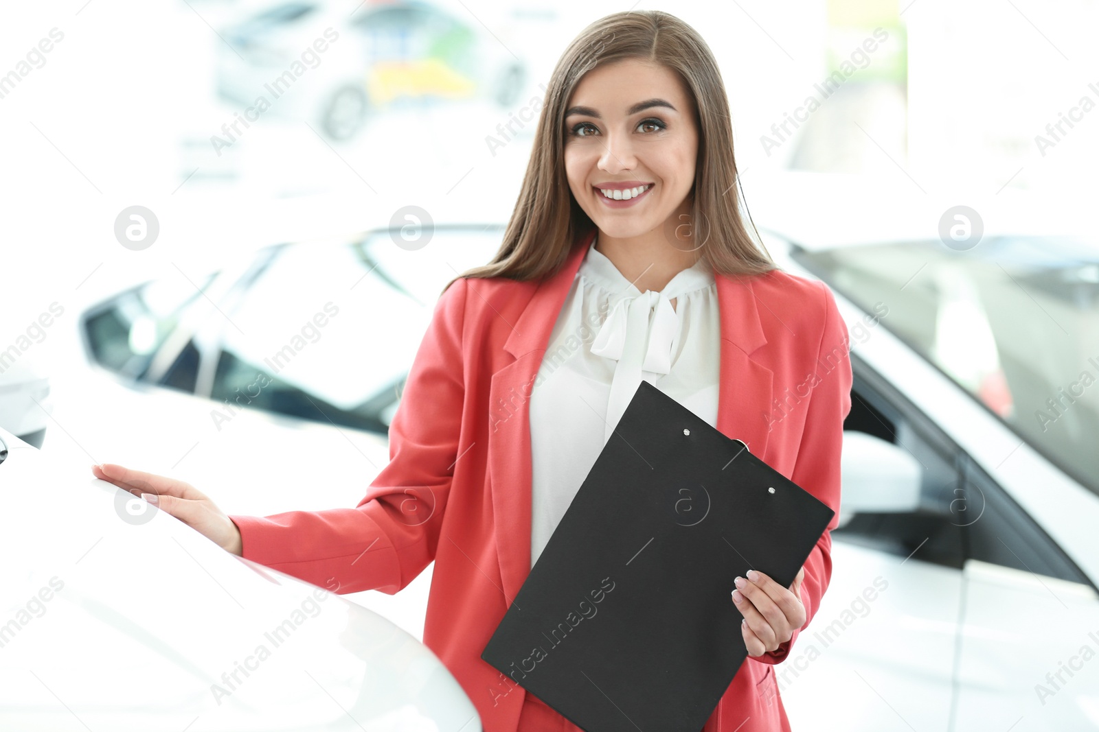 Photo of Young woman with clipboard in car salon