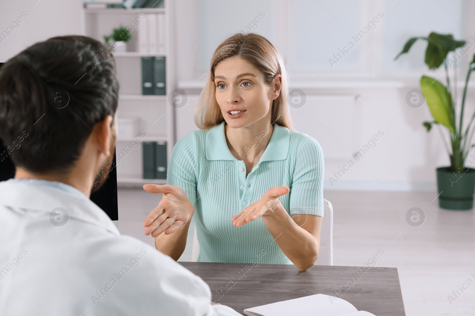 Photo of Doctor consulting patient at wooden table in clinic