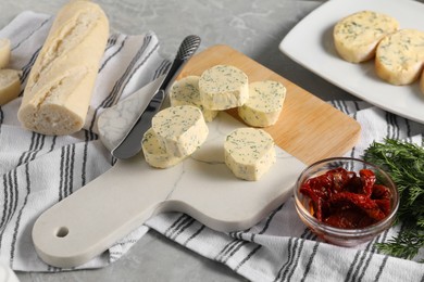 Photo of Tasty butter, dill, chili peppers and bread on grey marble table