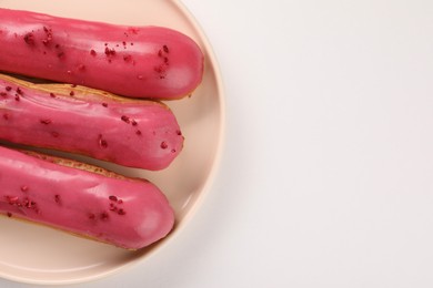 Photo of Delicious eclairs covered with glaze on white background, top view