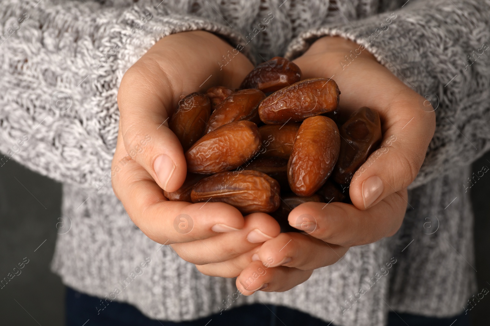 Photo of Woman holding handful of dried date fruits, closeup