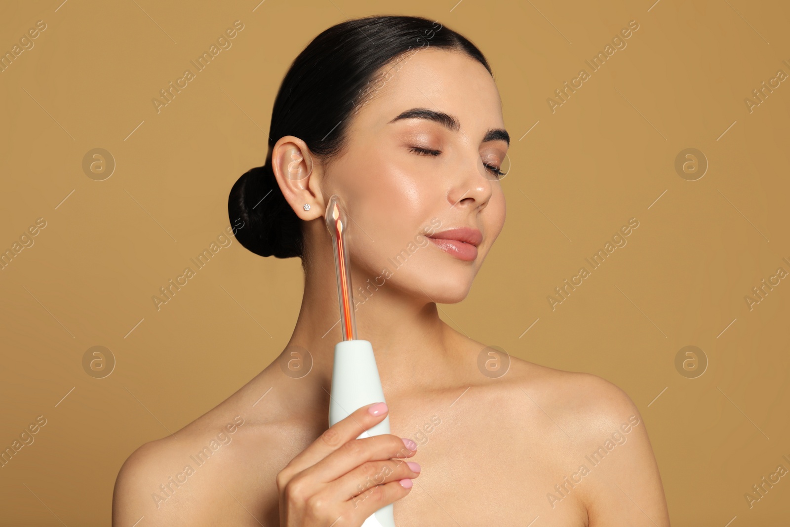 Photo of Woman using high frequency darsonval device on beige background. Space for text