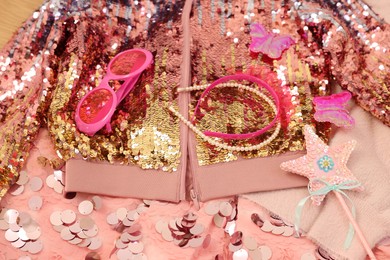 Photo of Stylish carnival costume with sequins, sunglasses, headbands and wand, above view