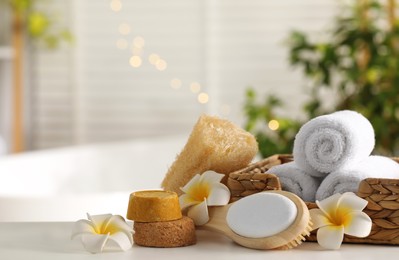 Photo of Composition with different spa products and plumeria flowers on white table in bathroom. Space for text