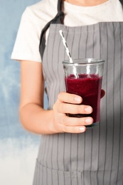 Photo of Woman with glass of beet smoothie on color background, closeup