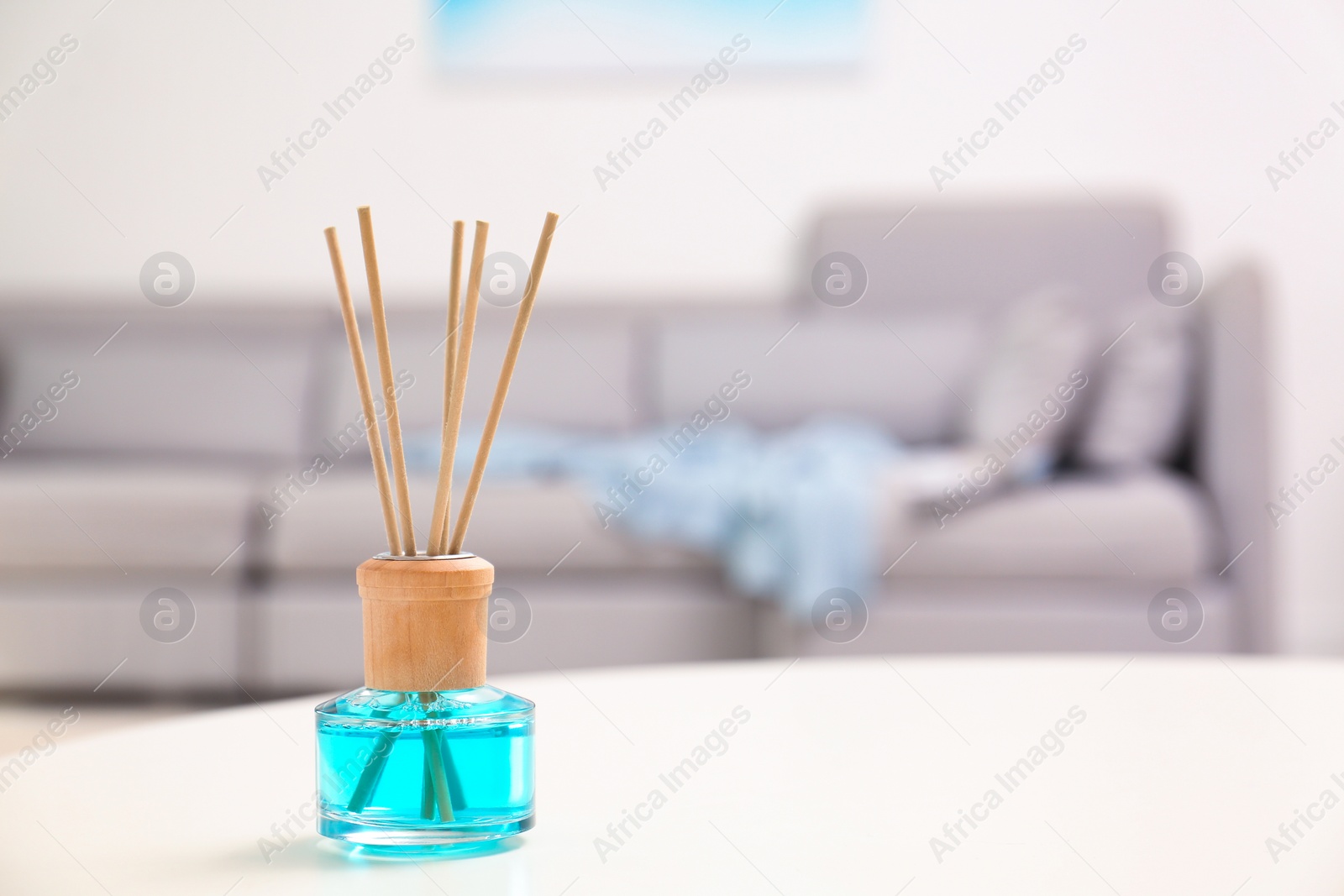 Photo of Reed air freshener with essential oil on table in room. Space for text