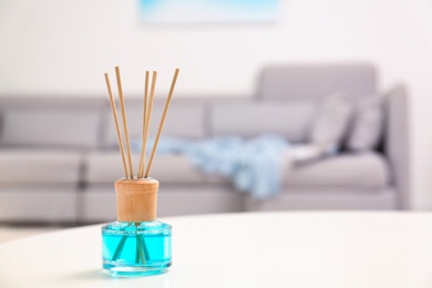 Reed air freshener with essential oil on table in room. Space for text