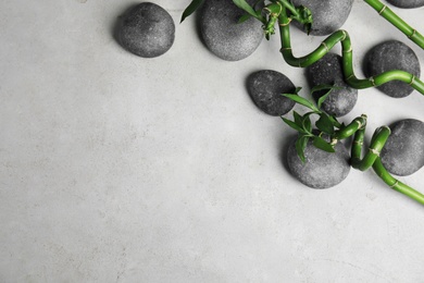 Photo of Zen stones and bamboo on grey background, top view with space for text