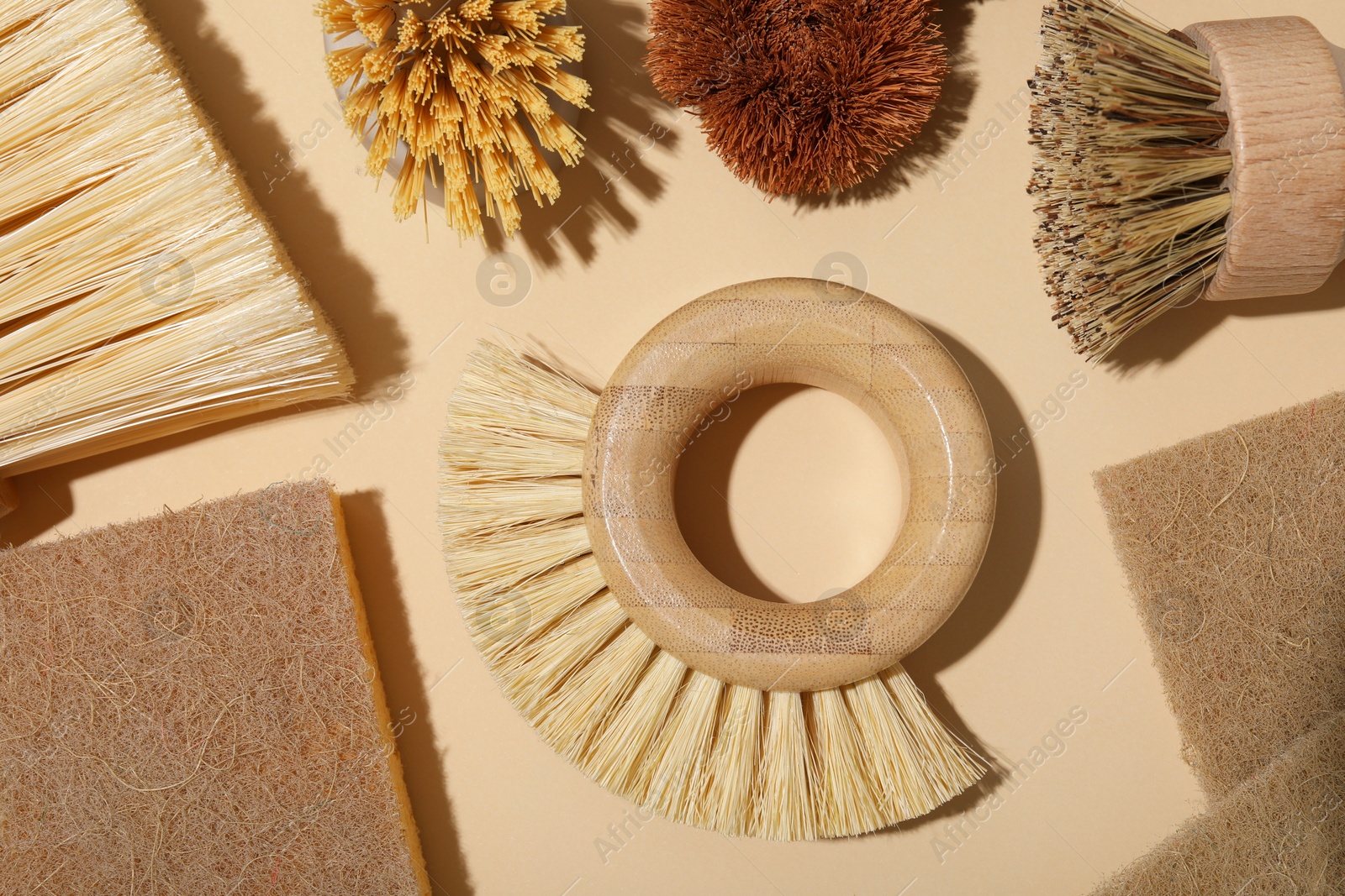 Photo of Cleaning brushes and sponges on beige background, flat lay