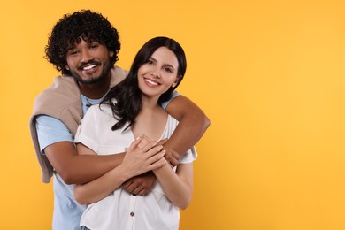 Photo of International dating. Happy couple hugging on yellow background, space for text