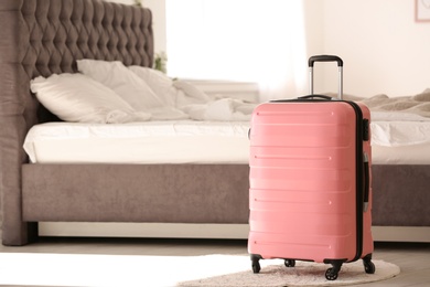 Photo of Colorful suitcase packed for journey in bedroom. Space for text